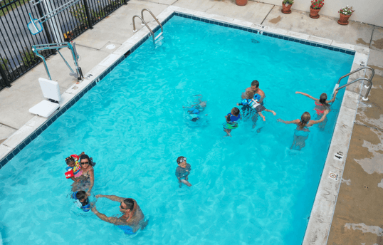 Adults and children swimming in the new outdoor pool at the Barefoot Mailman.