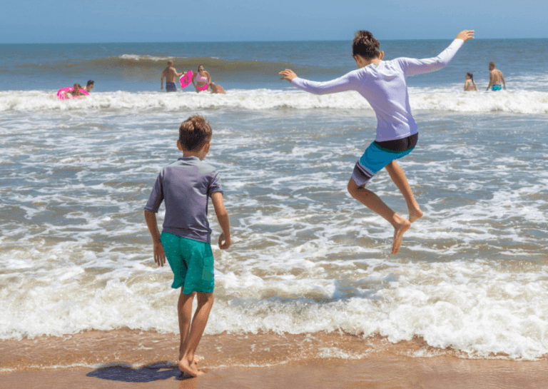 Two young boys jumping in the ocean at Castle in the Sand.